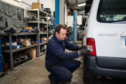 Mécanicien remplaçant le feu arrière d'un Peugeot Partner dans un atelier automobile